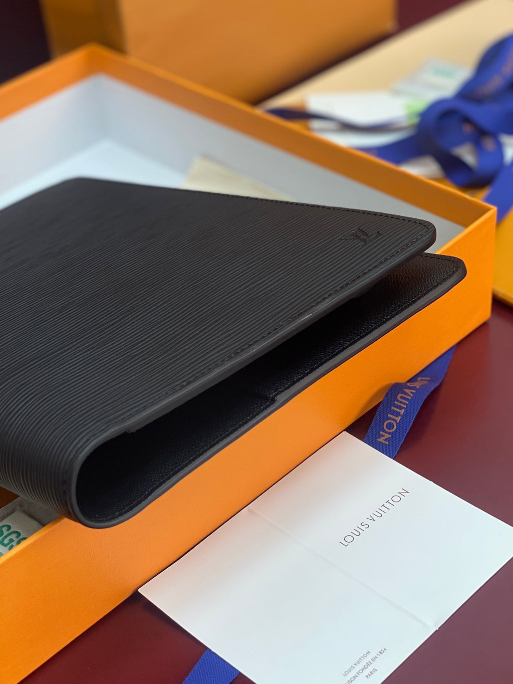 Dark textured leather wallet corner close-up in orange gift box