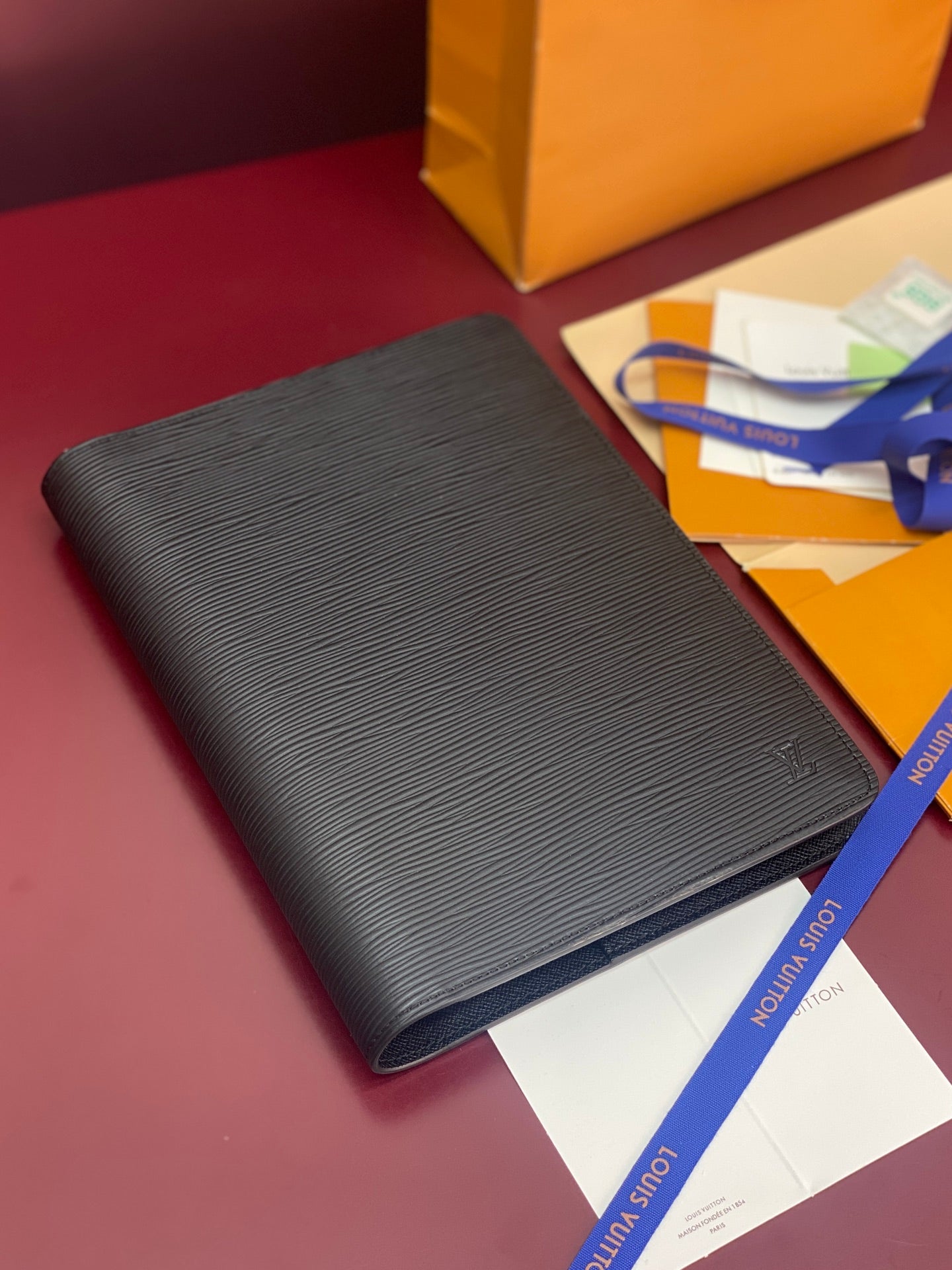 Dark textured leather wallet with slim profile, angled view