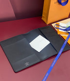 Dark leather wallet with snap closure, open gift box with papers