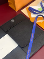 Dark textured leather wallet with logo panel, laid on packaging