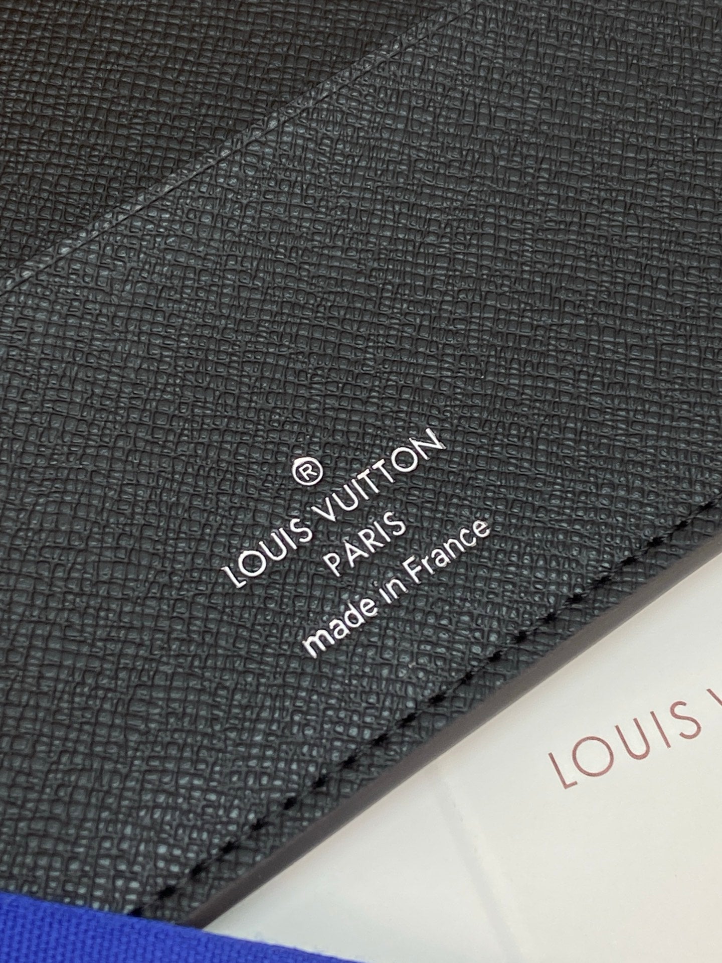 Louis Vuitton small bag close-up of stitched logo text on dark textured leather