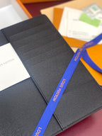 Louis Vuitton dark leather card holder with textured surface and fold