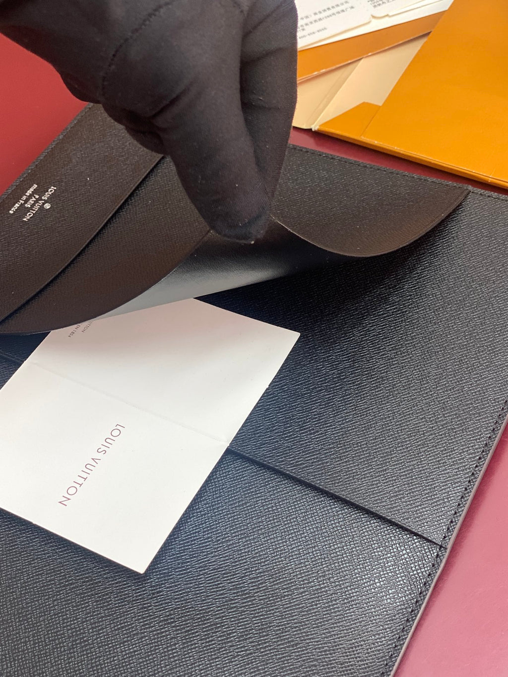 Louis Vuitton small bag with dark textured leather, opened with insert cards