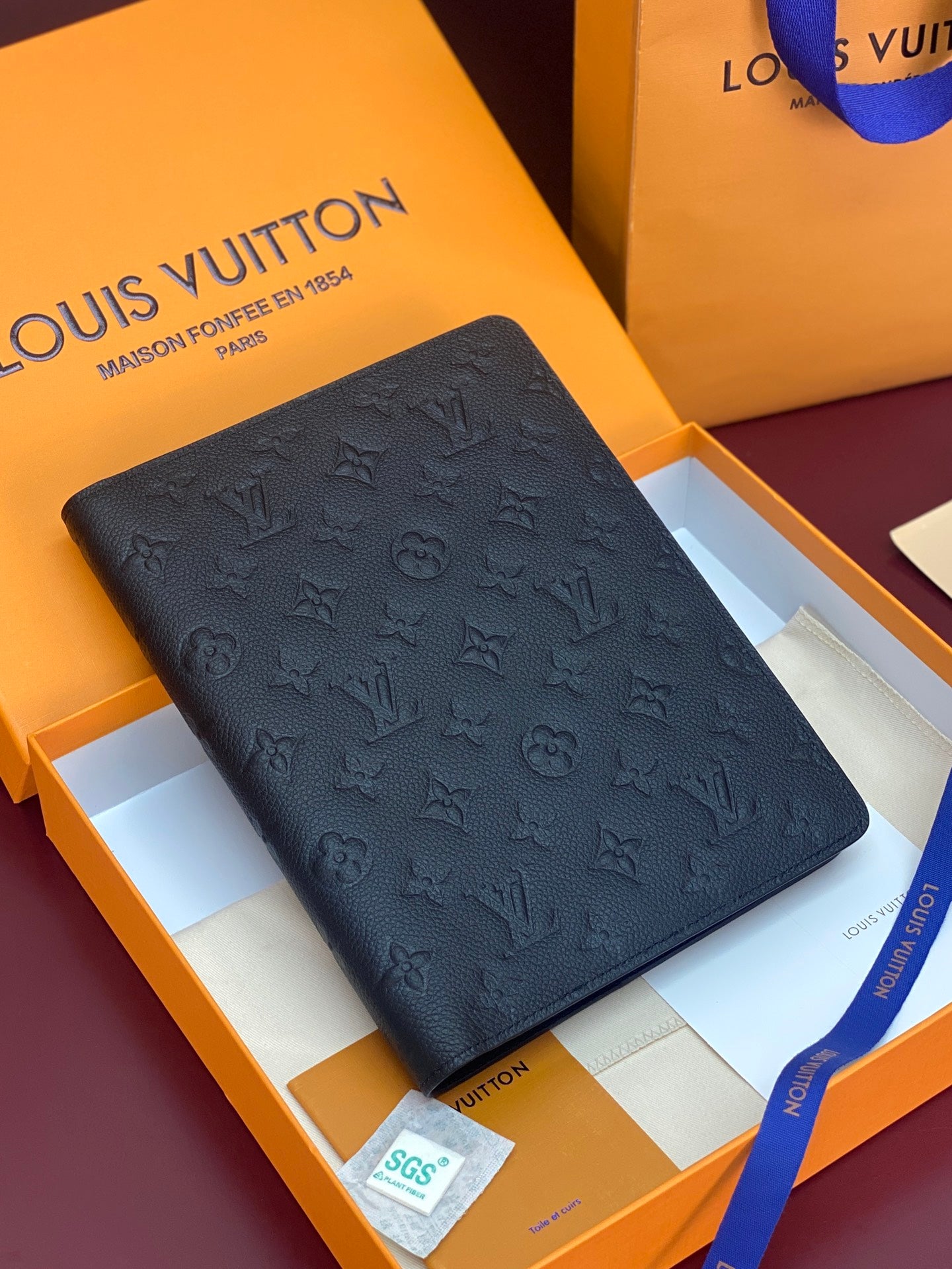 Black monogram leather wallet with embossed pattern, front view.