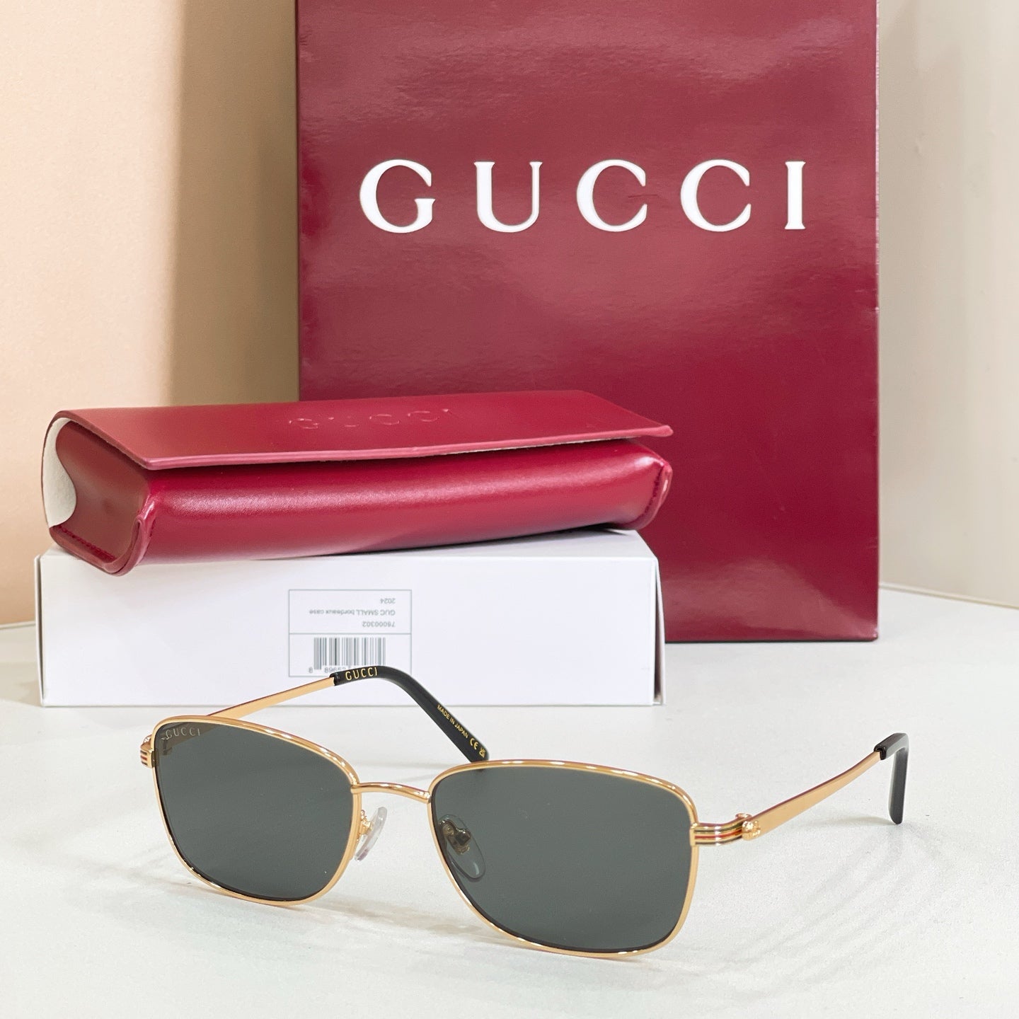 Gold-tone metal sunglasses with dark gray tinted lenses and logo-striped temple