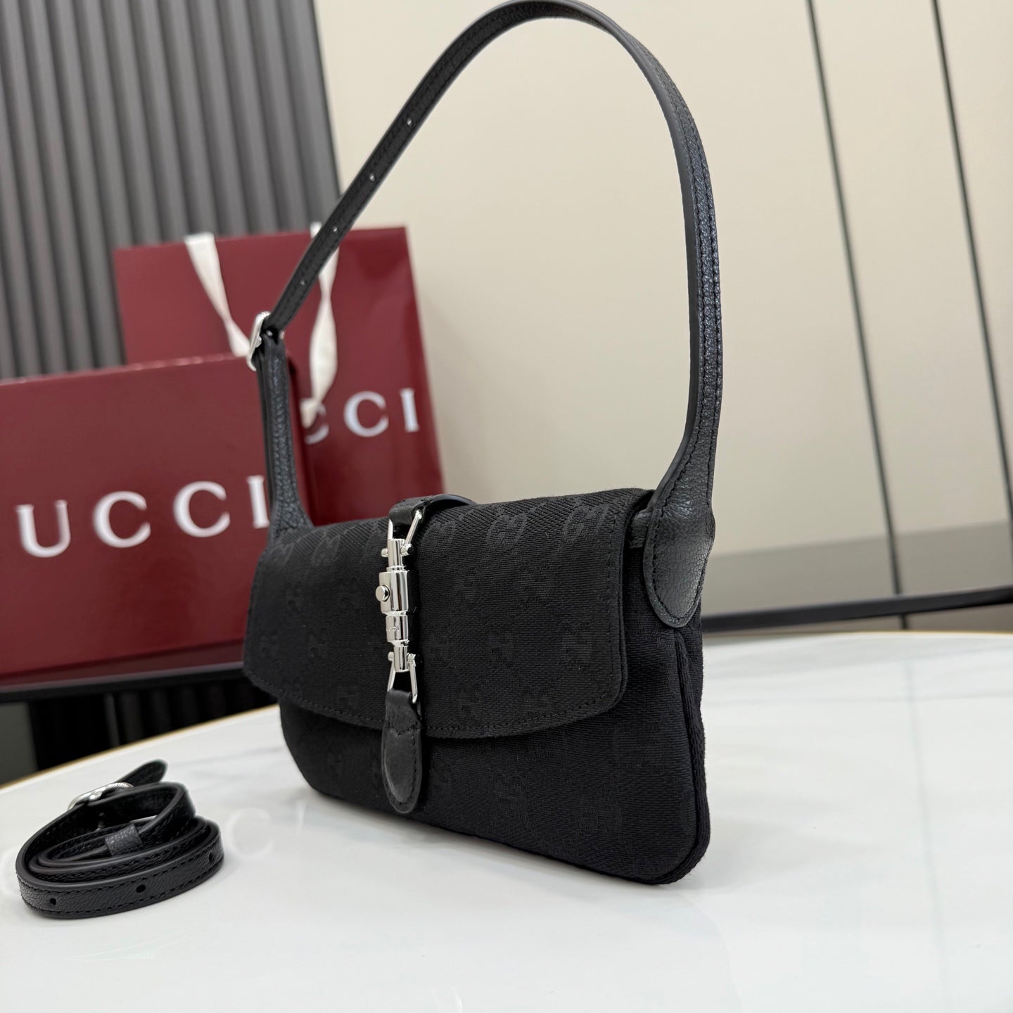 Black Gucci shoulder bag with flap front, top handle, and silver chain latch hardware.