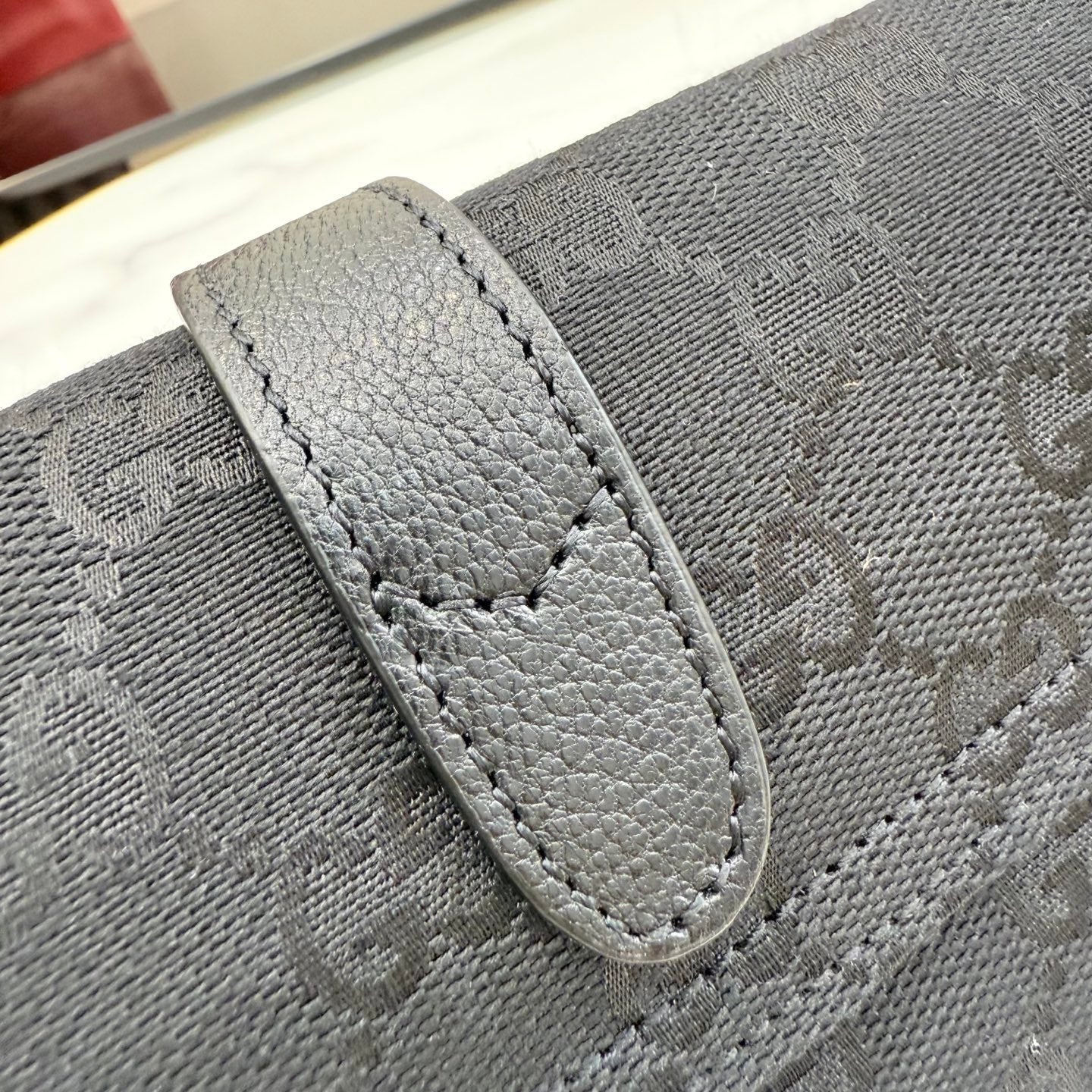 Gucci bag detail, light gray logo canvas with stitched leather trim and tab