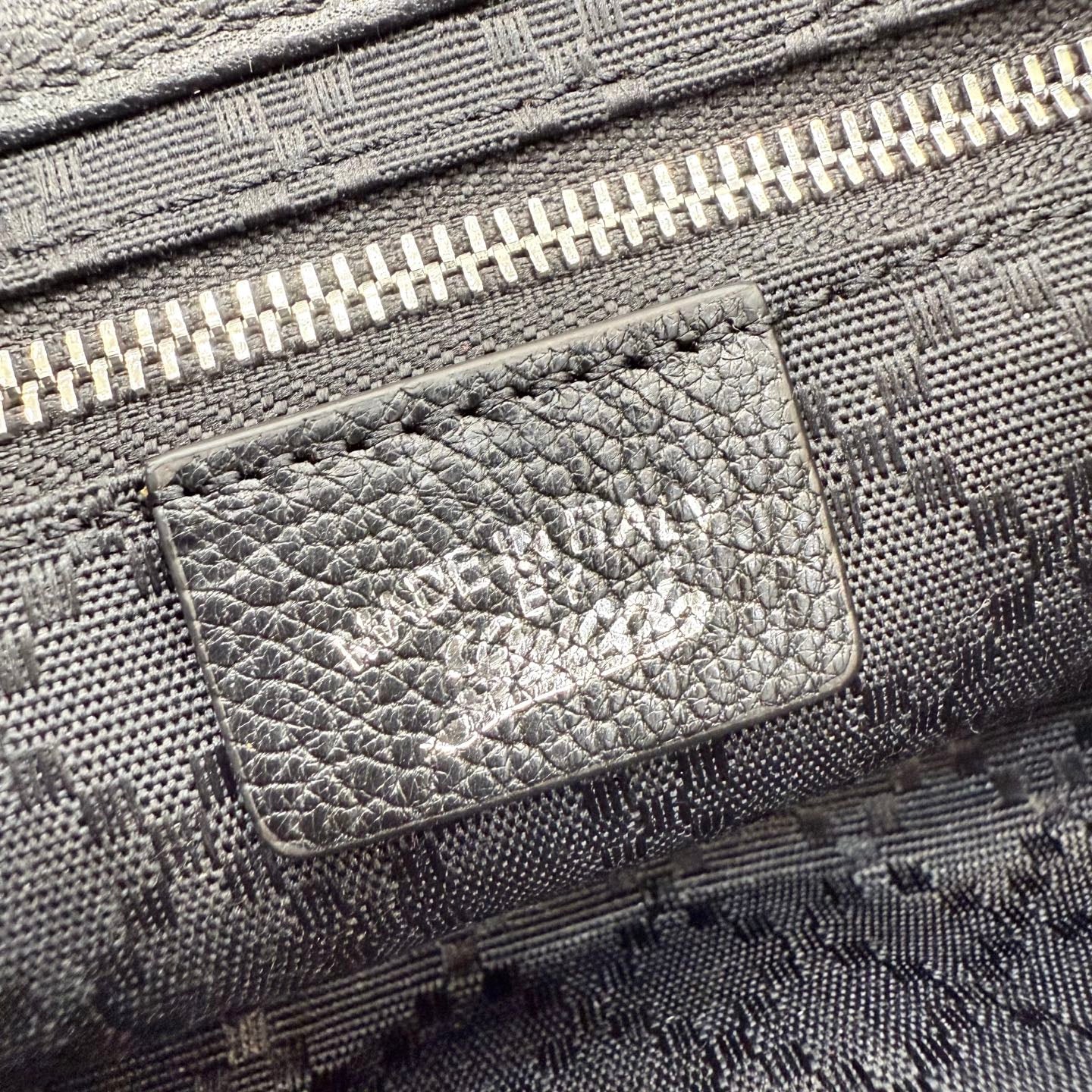 Gray Gucci bag interior pocket with stitched leather patch and zipper track detail.
