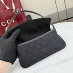 Gray Gucci mini bag with monogram exterior and top handle, held in a hand.