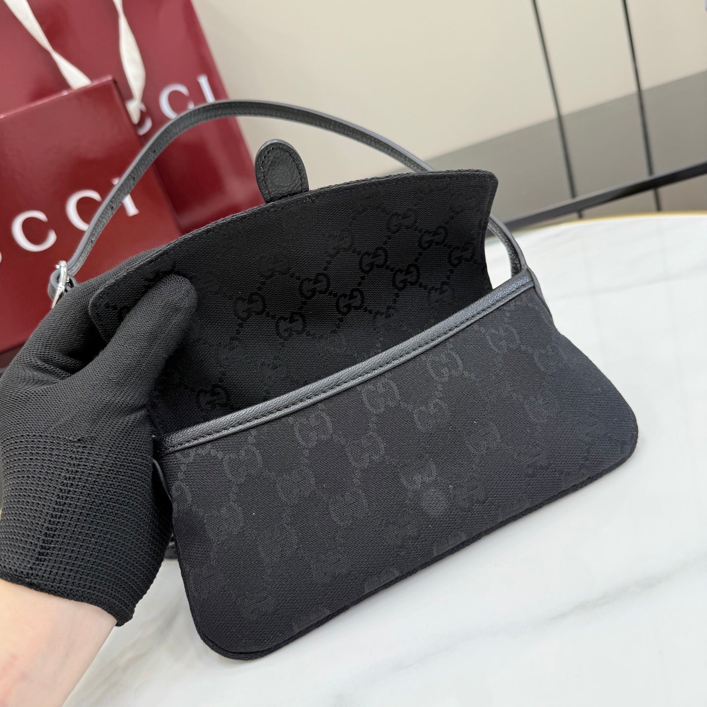 Gray Gucci mini bag with monogram exterior and top handle, held in a hand.
