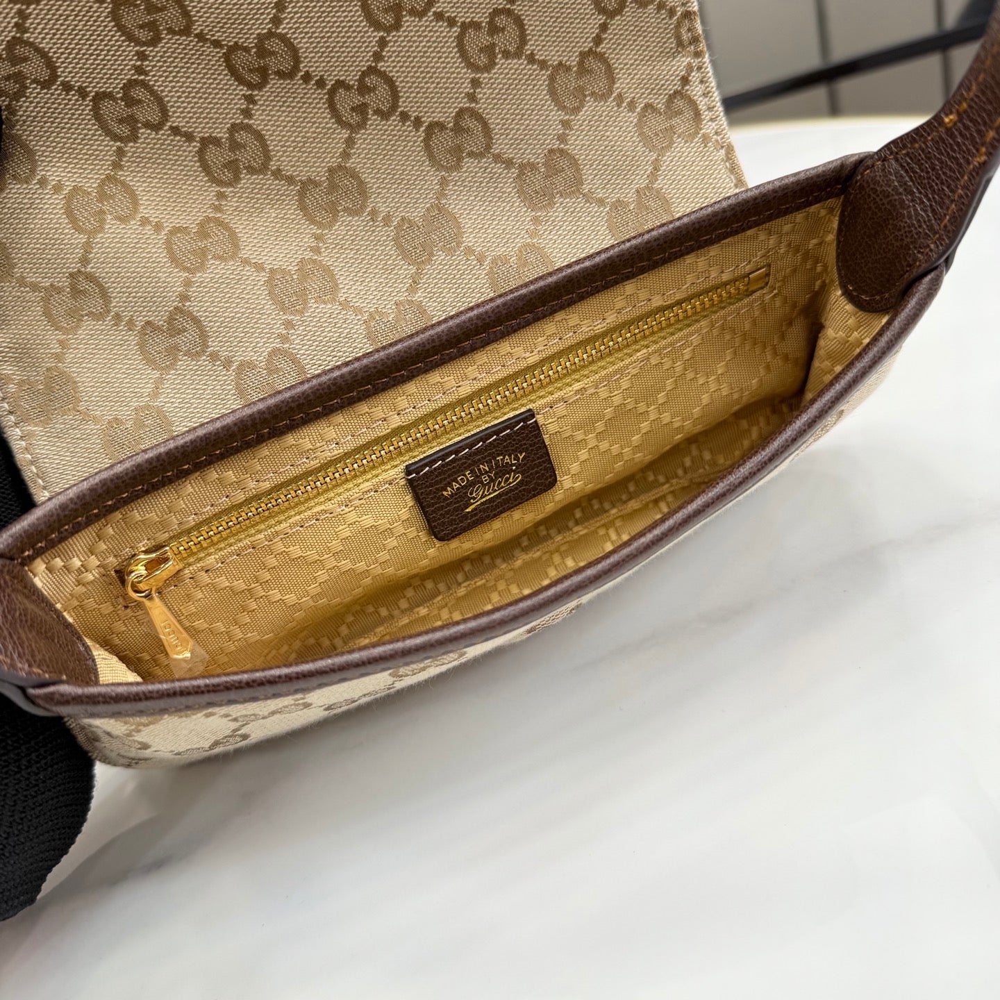 Beige interior of GG-pattern shoulder bag with gold zipper and leather brand patch