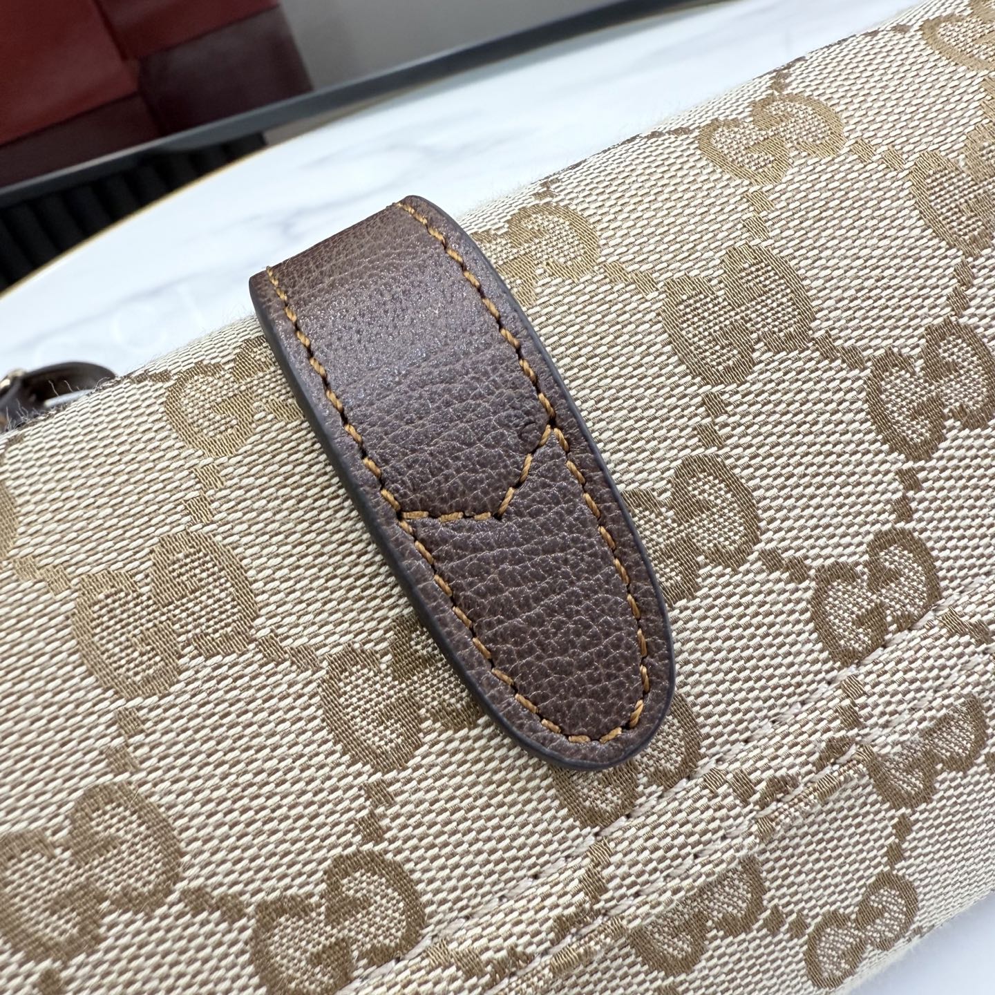 Monogram canvas bag handle with brown leather tab and stitched edge