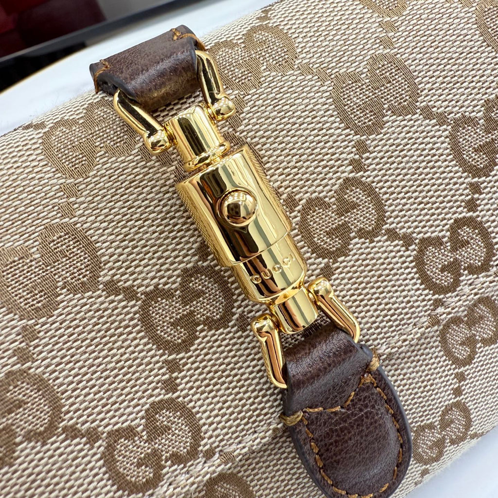 GG-pattern bag clasp close-up with gold-tone lock and dark brown leather strap