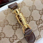 GG-pattern bag clasp close-up with gold-tone lock and dark brown leather strap