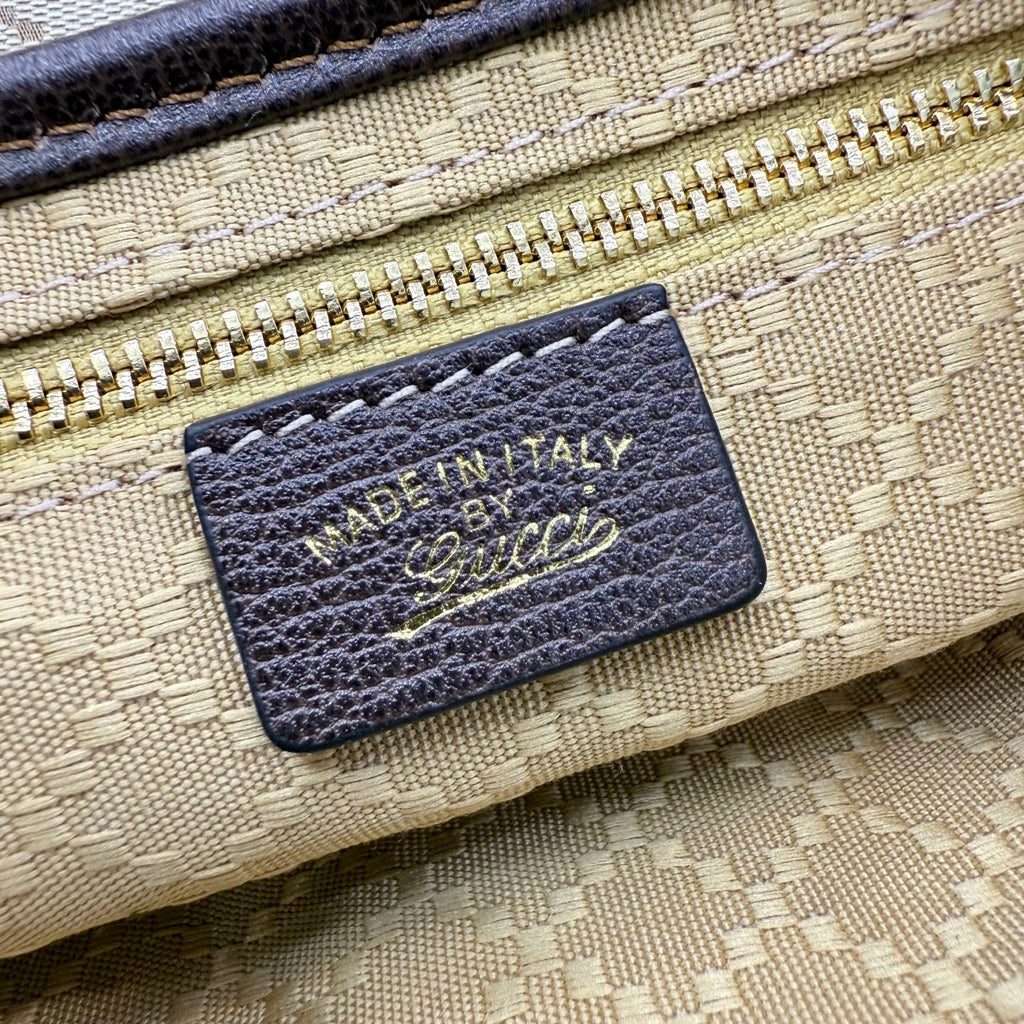 Beige bag leather label with dark border, showing Made in Italy and signature-style logo