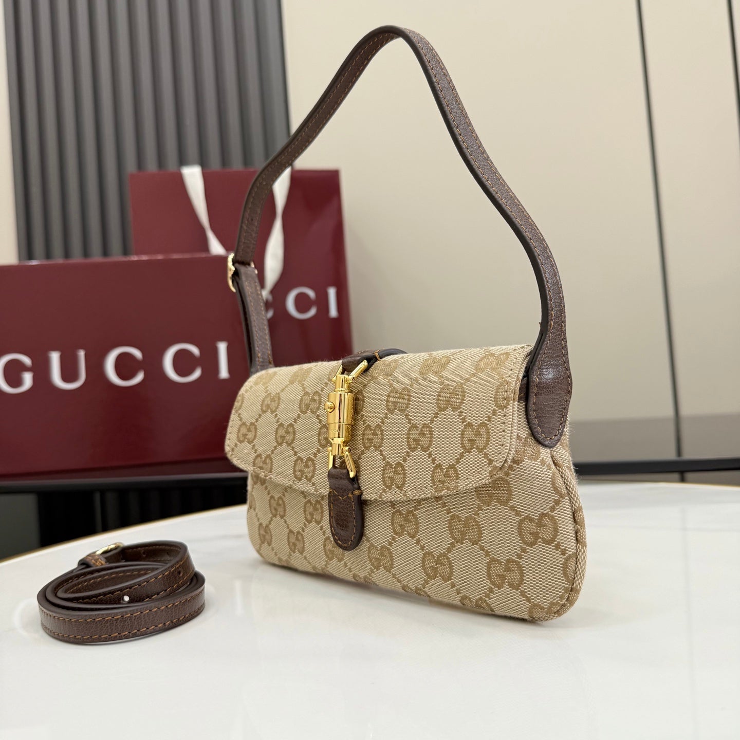Beige GG-pattern small hobo shoulder bag with dark brown leather accents and gold clasp