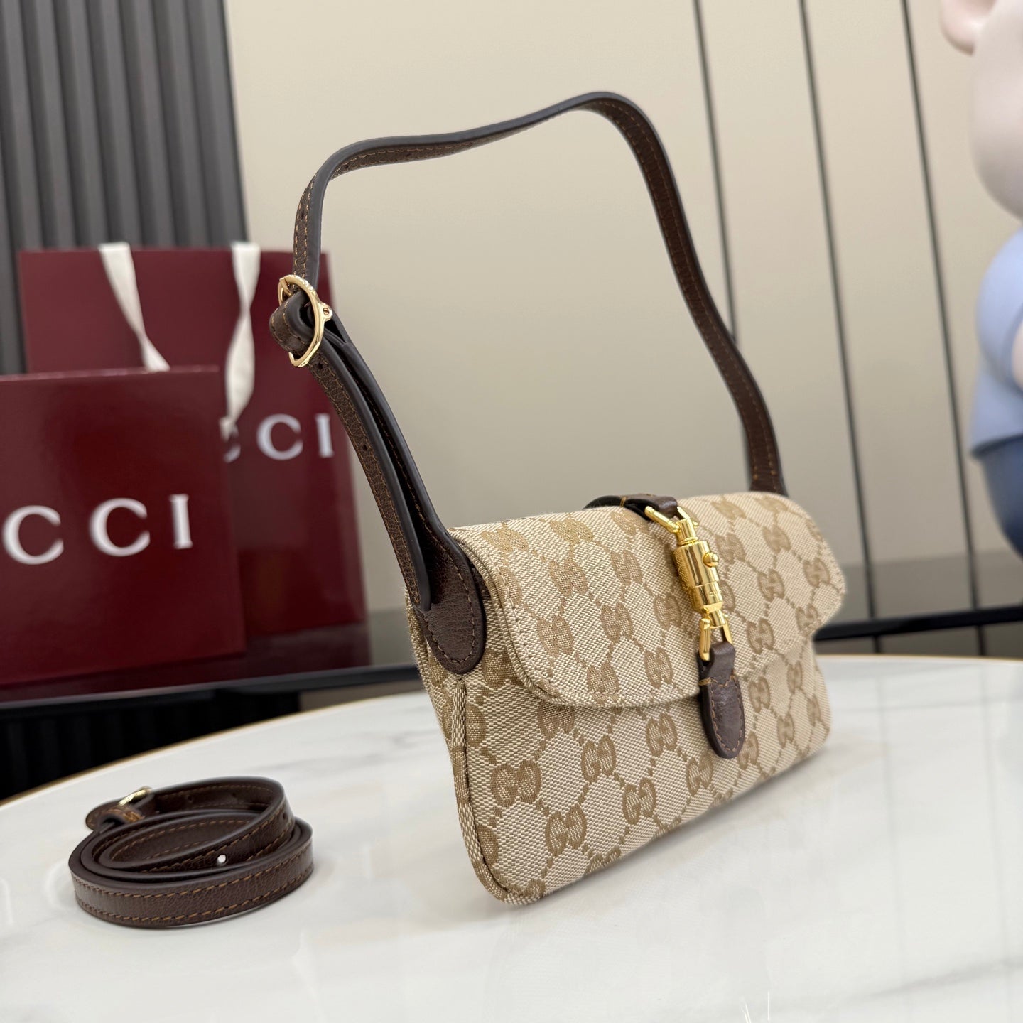 Beige GG-pattern small shoulder bag with dark brown trim, gold hardware, and strap
