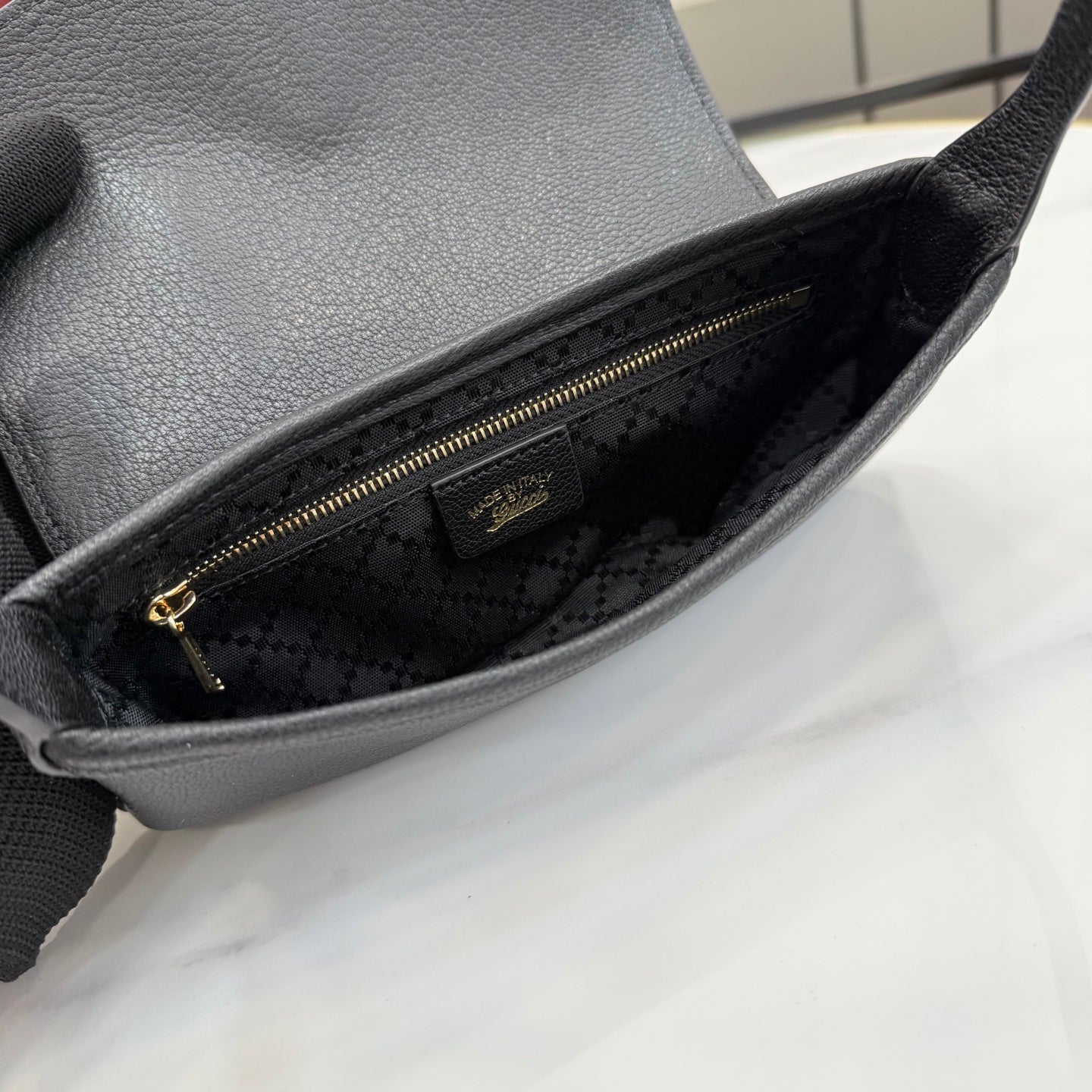 Black Gucci shoulder bag interior with fabric lining and zipper pocket, close-up