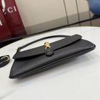 Black Gucci shoulder bag with top handle and flap, gold clasp on front, flat lay
