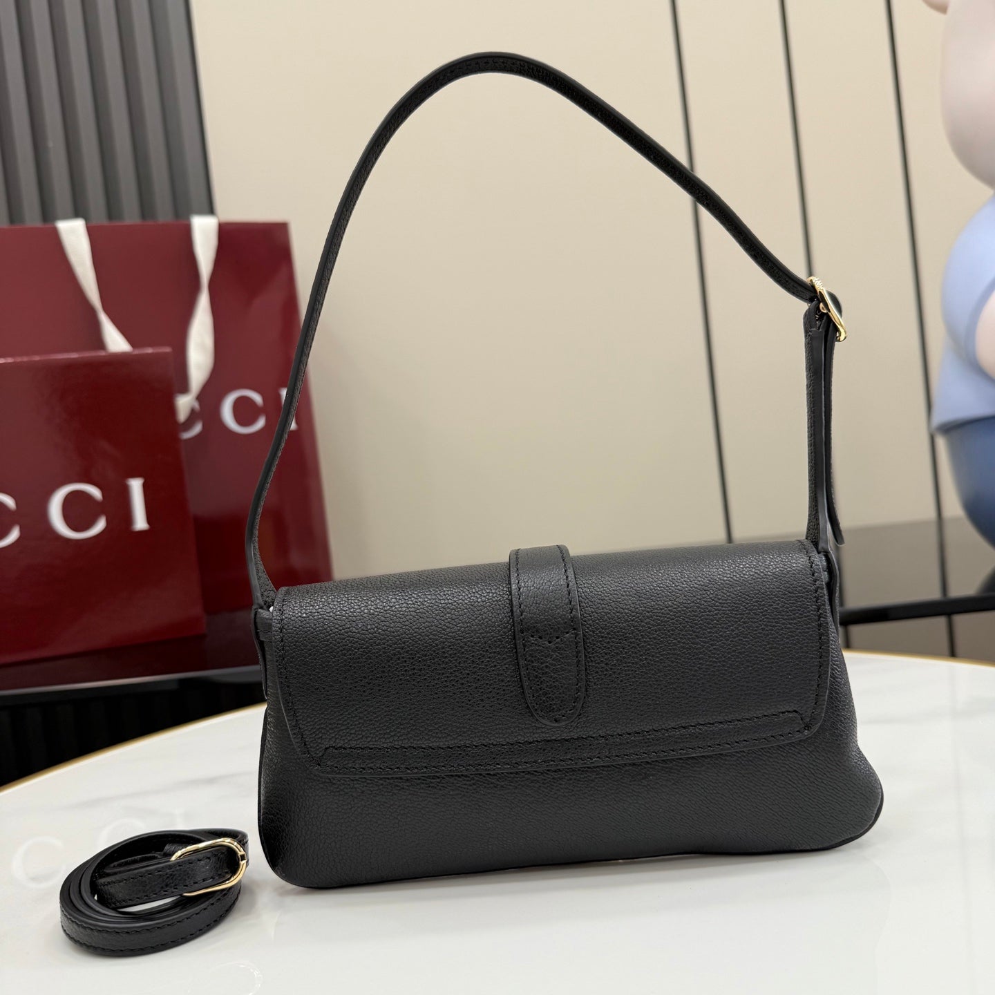 Black Gucci small shoulder bag with top handle and flap front, side profile