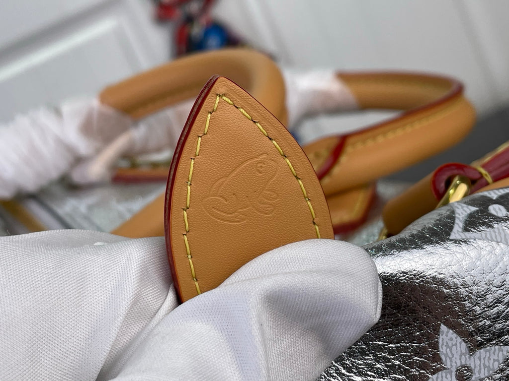 Tan leather side strap with embossed emblem on monogram canvas bag