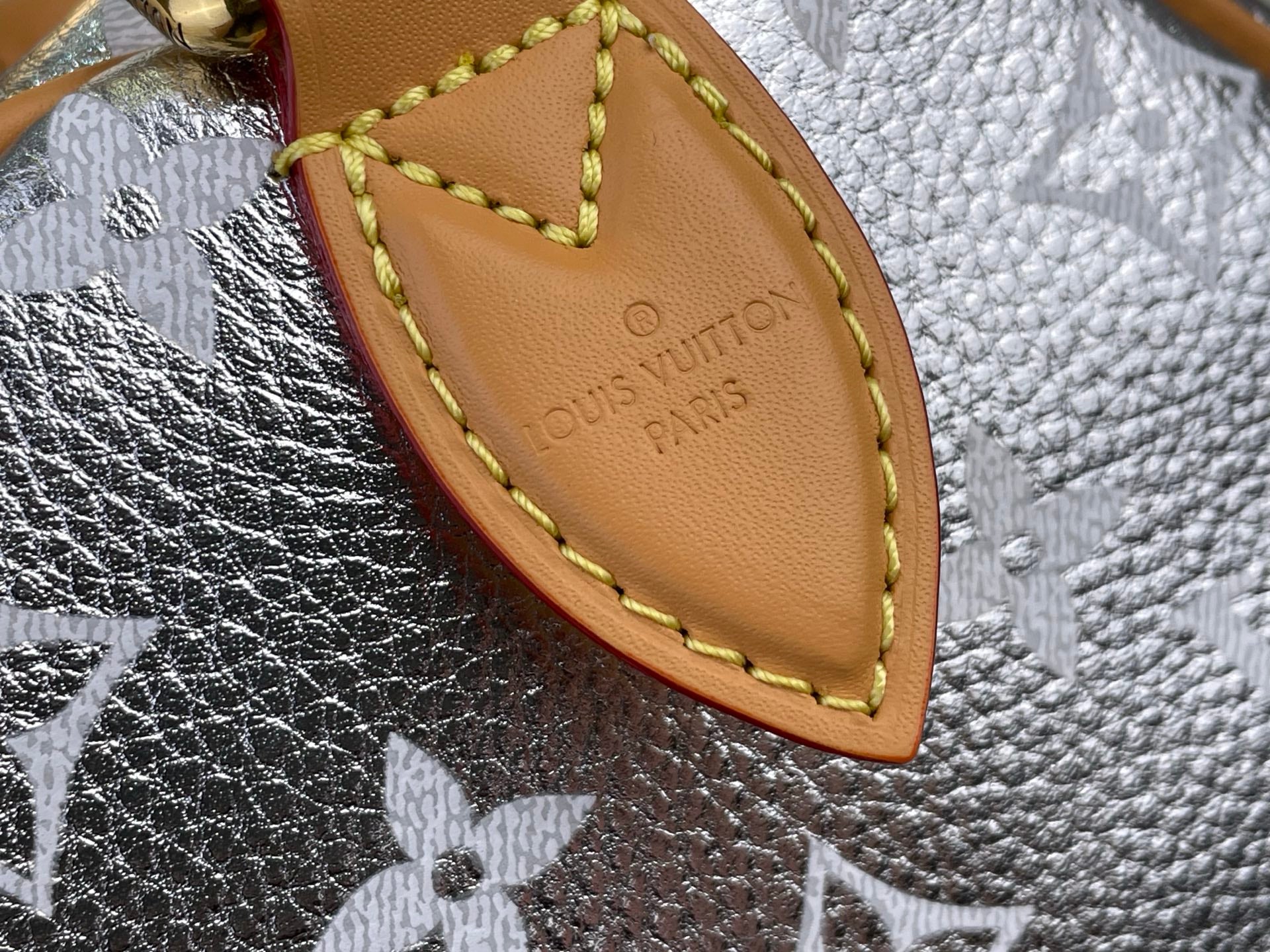 Tan leather tab with Louis Vuitton Paris imprint and yellow edge stitching