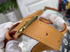 Tan leather wrist strap with gold clasp and stitching on monogram canvas bag