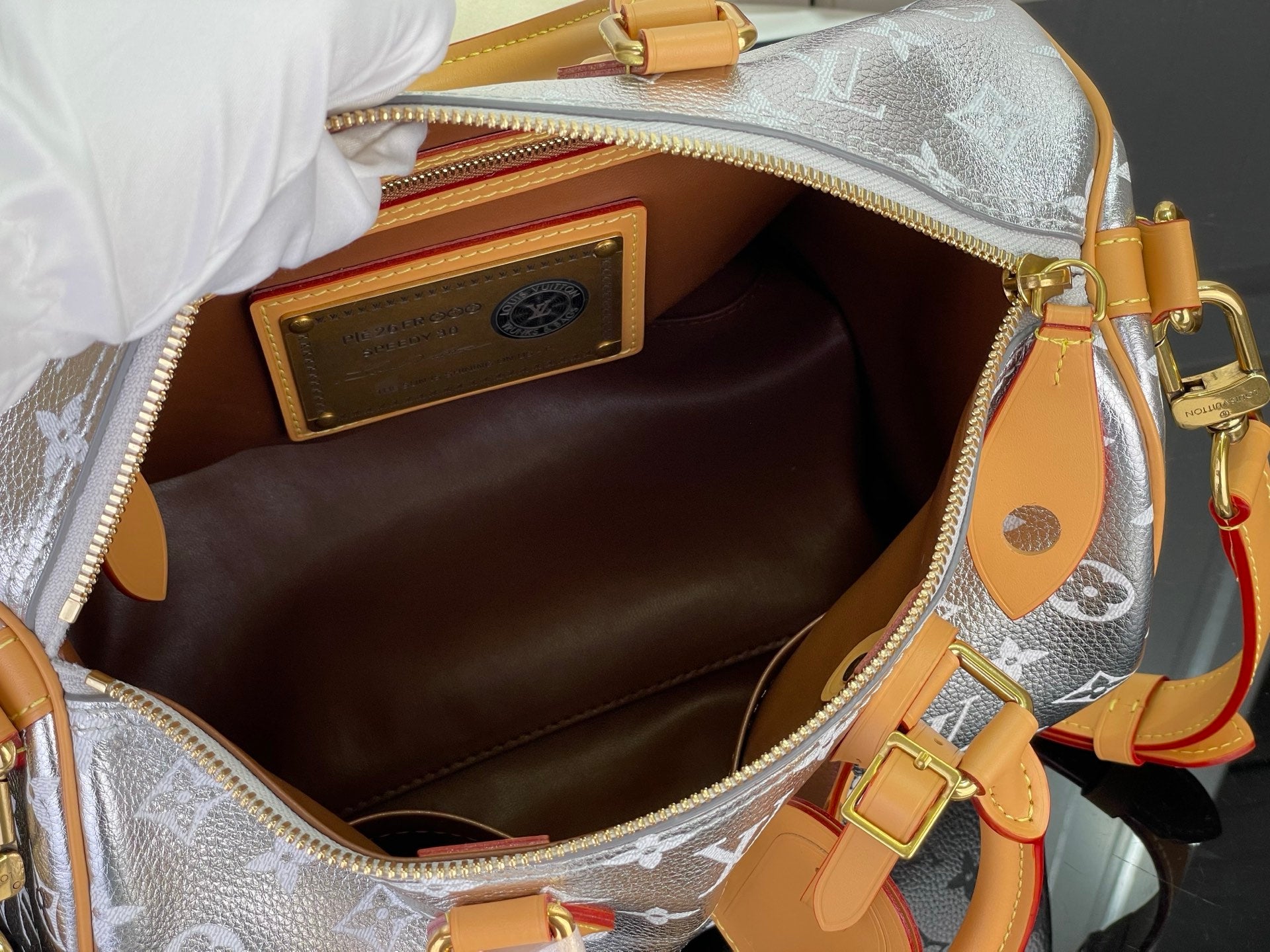 Open monogram canvas bag interior with tan lining and gold zipper edge