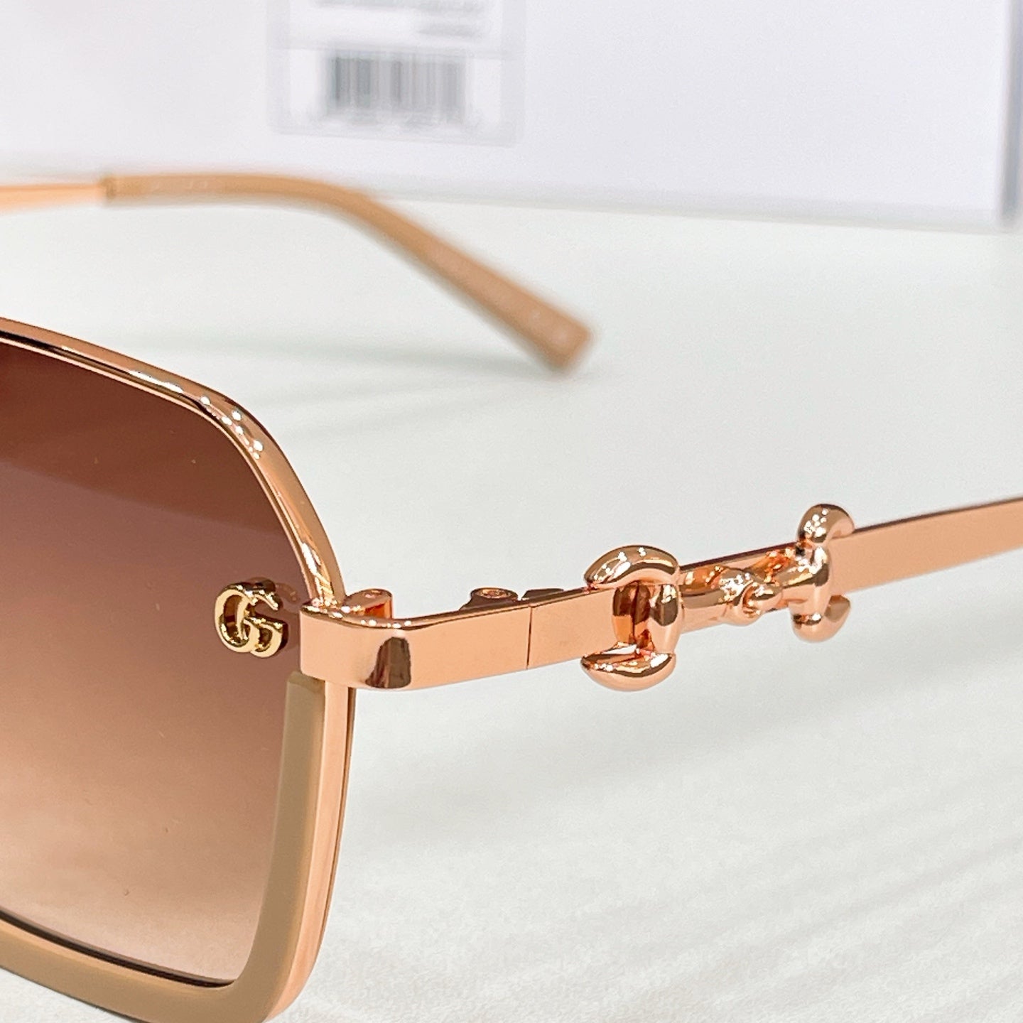 Close-up of gold sunglasses temple with metal emblem and hinge detail