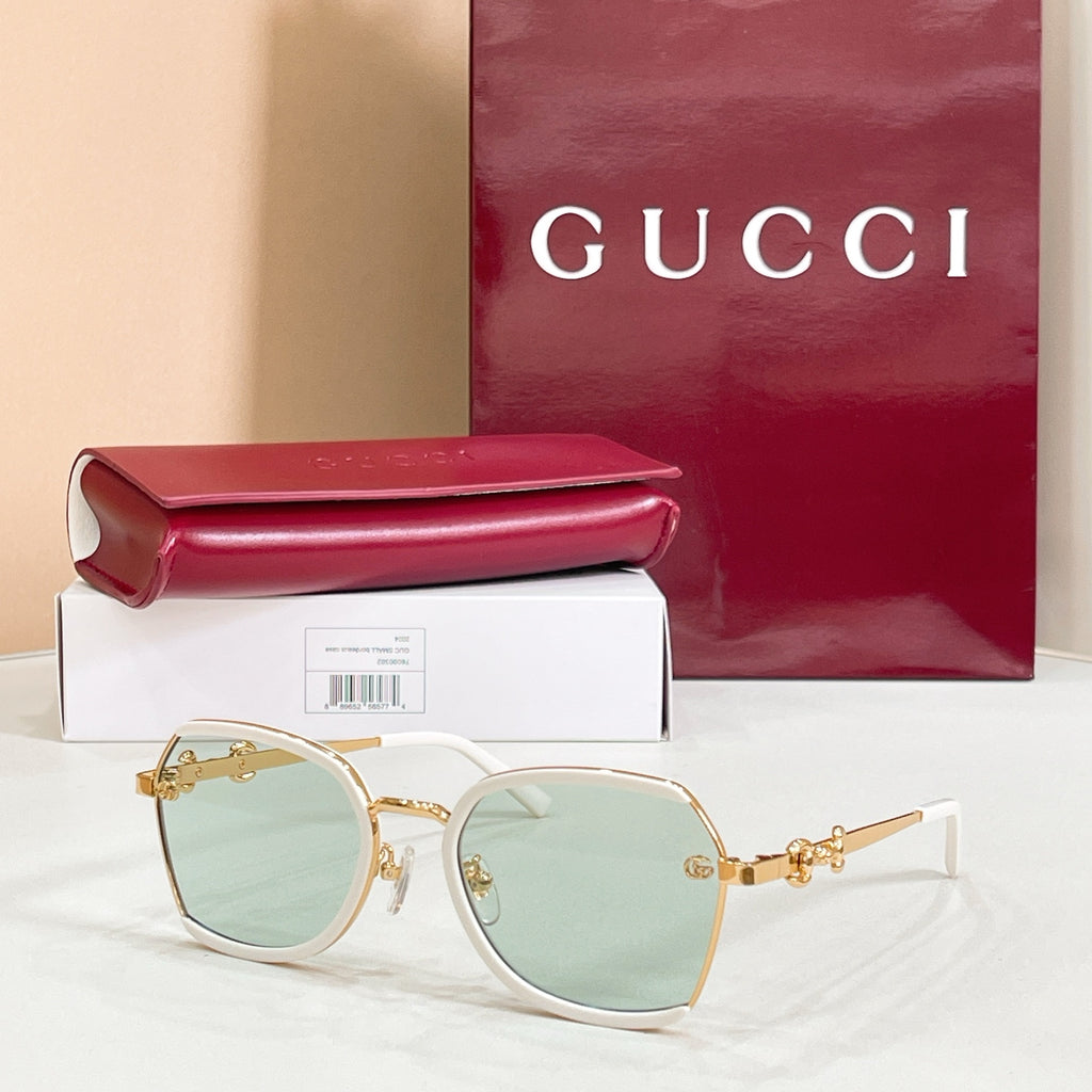 Light frame round sunglasses with mint-green lenses and gold logo hinges.