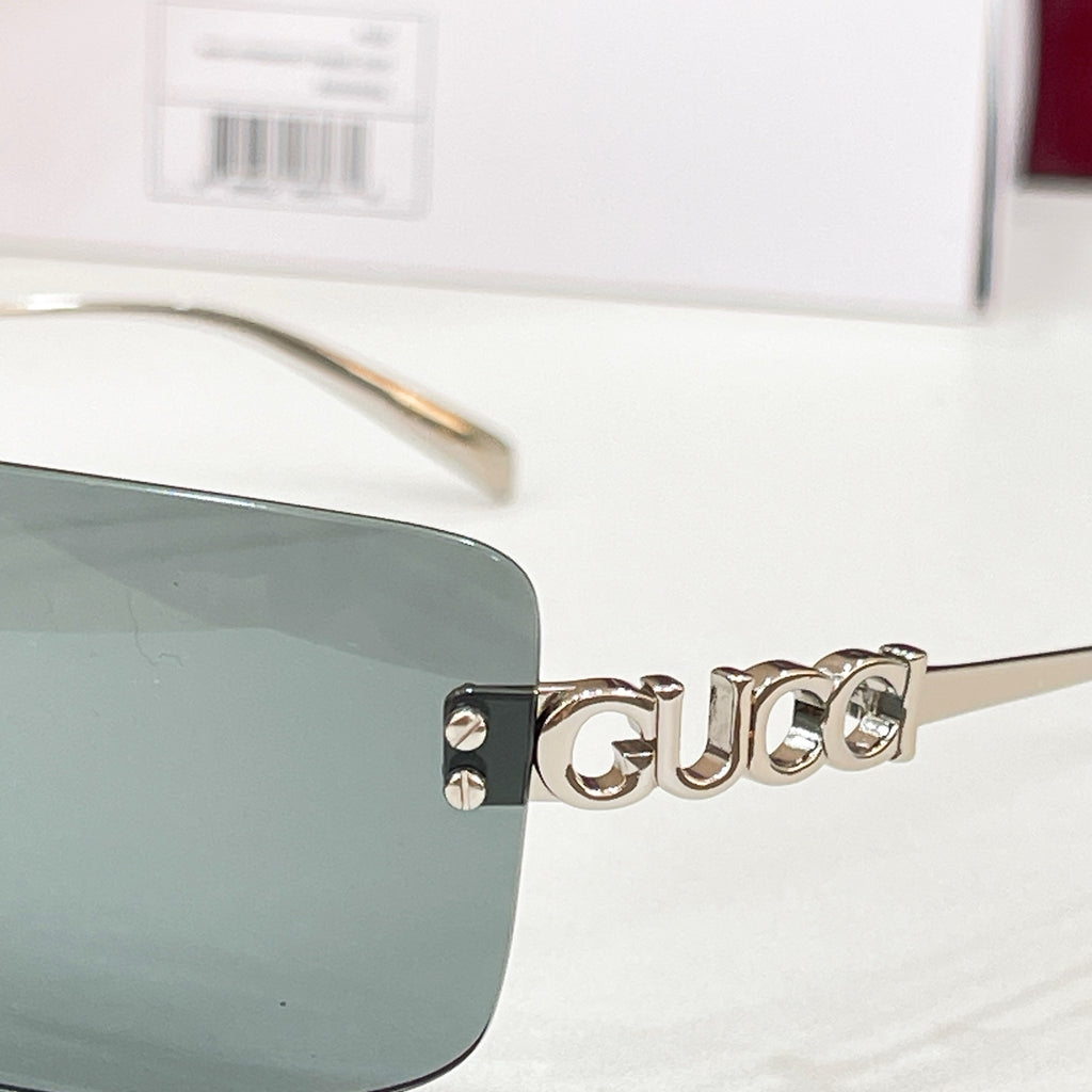 Sunglasses close-up with gold logo temple and blue-green lenses