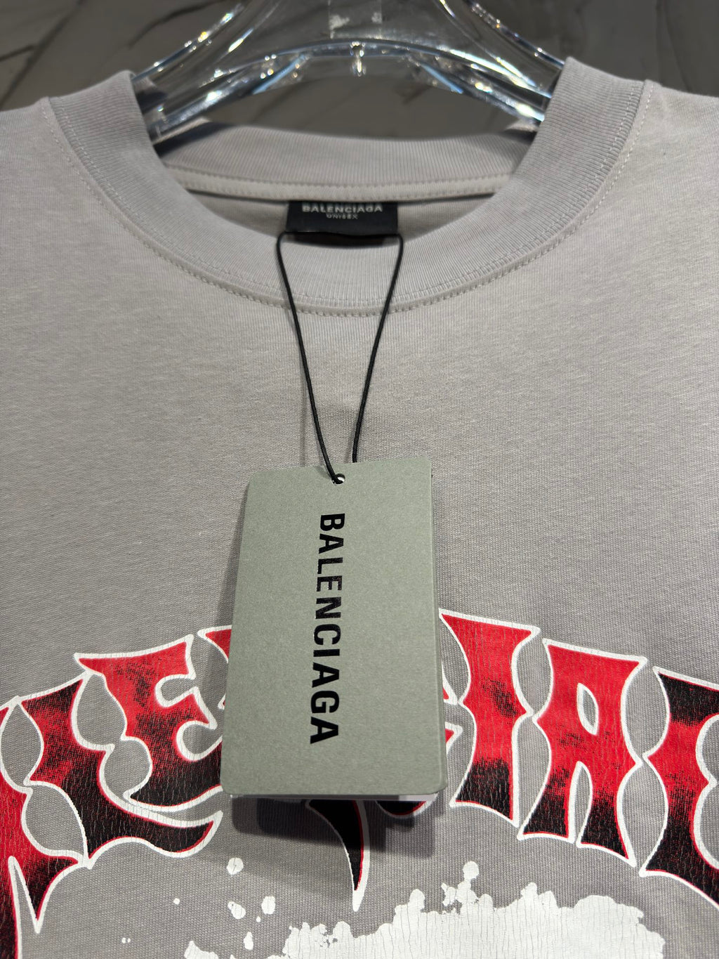 Light gray crewneck T-shirt with hanging Balenciaga tag at the neckline
