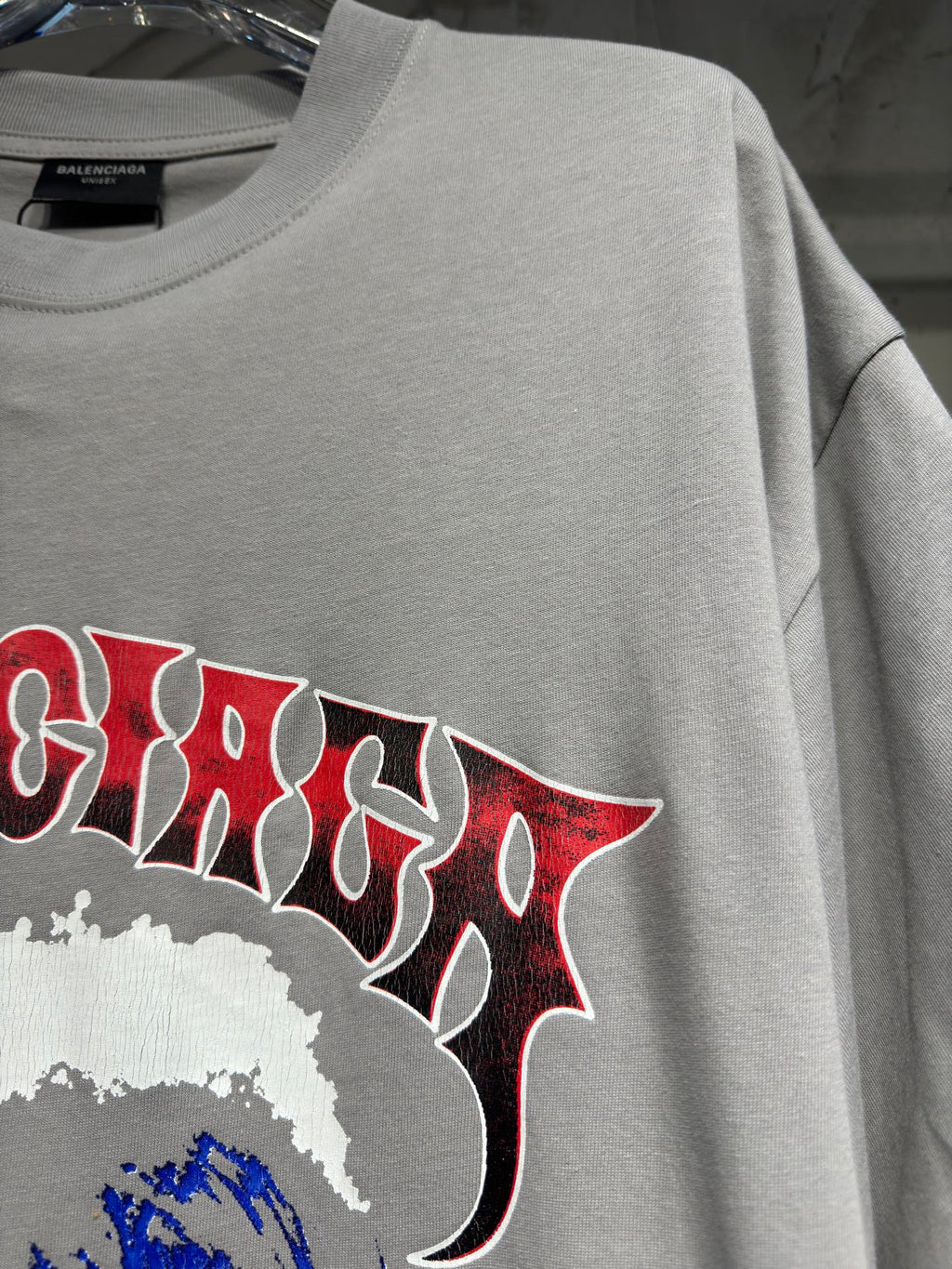Light gray T-shirt showing red graphic lettering with white splatter detail