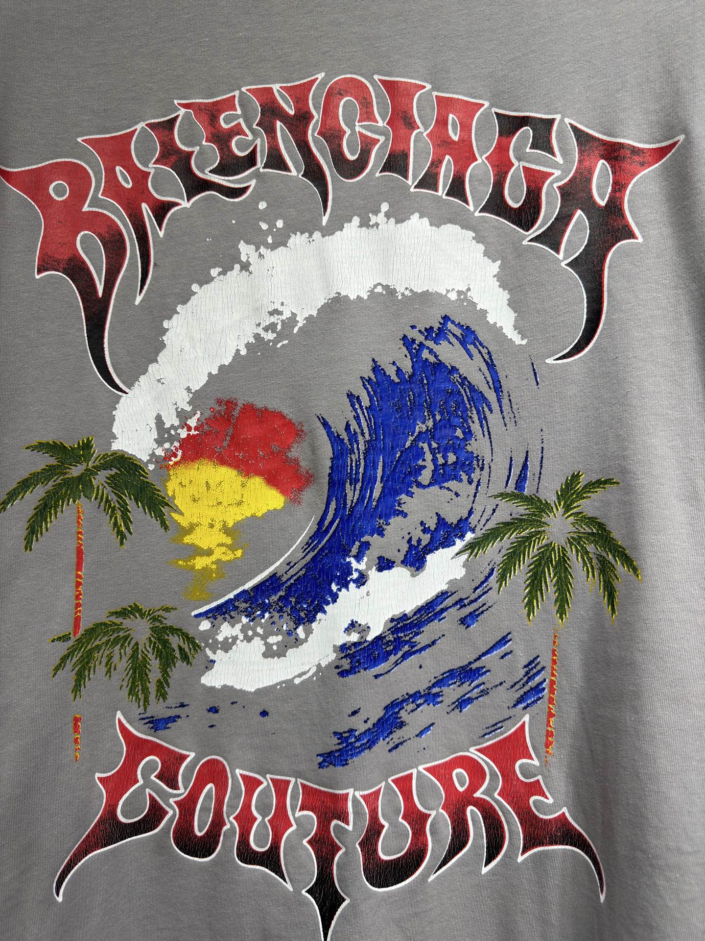 Light gray short-sleeve T-shirt with colorful face graphic, palms, and “Couture” text