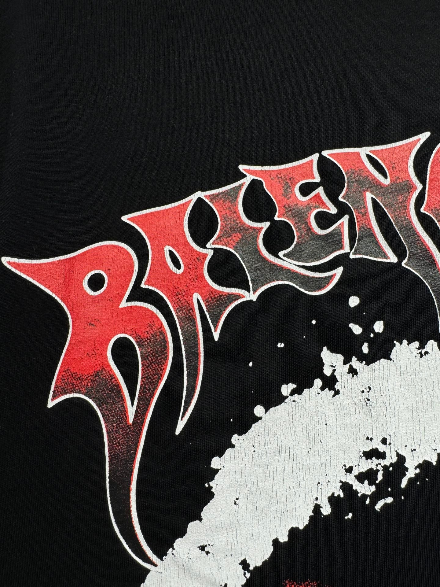 Black T-shirt close-up with red-and-white stylized lettering and paint texture
