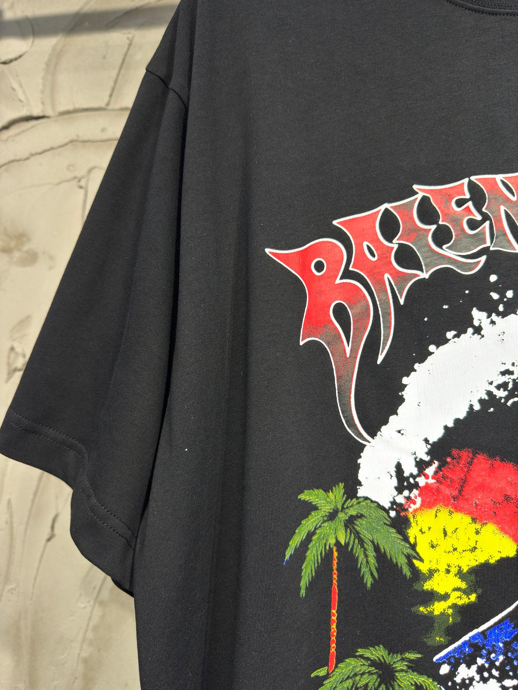 Charcoal T-shirt with large red-and-white graphic swirl and palm accents