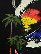 Black graphic T-shirt close-up with palm trees and colorful globe detail