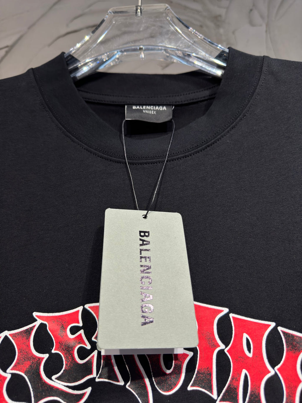 Black T-shirt on hanger with visible collar and hanging retail tag