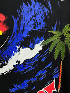 Black graphic T-shirt close-up with blue paint strokes and palm tree detail