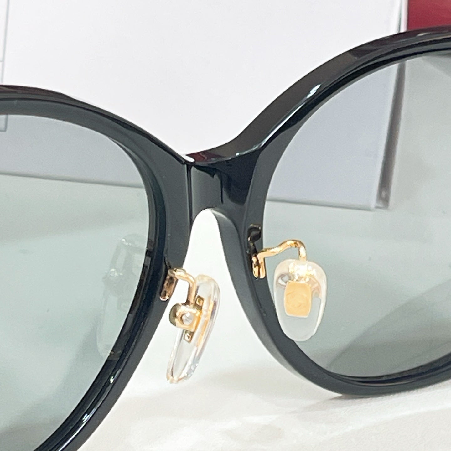 Black sunglasses close-up with gold-tone emblem at temple