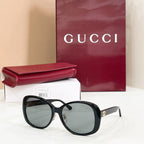 Black oversized sunglasses with dark lenses and striped temple accents
