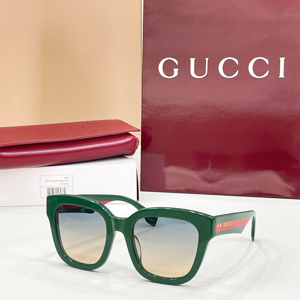 Green square eyeglass frames with clear lenses and Gucci logo temples.