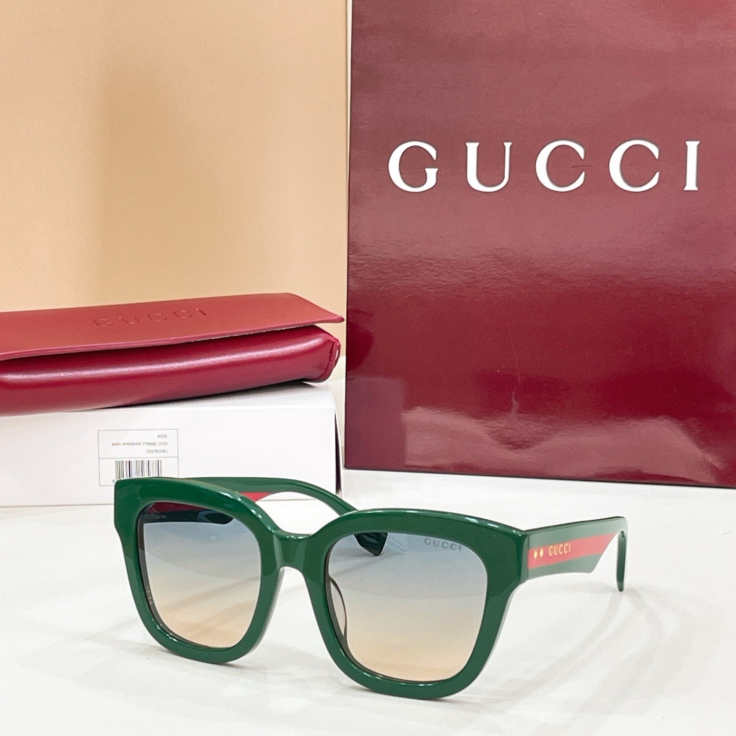 Green square eyeglass frames with clear lenses and Gucci logo temples.
