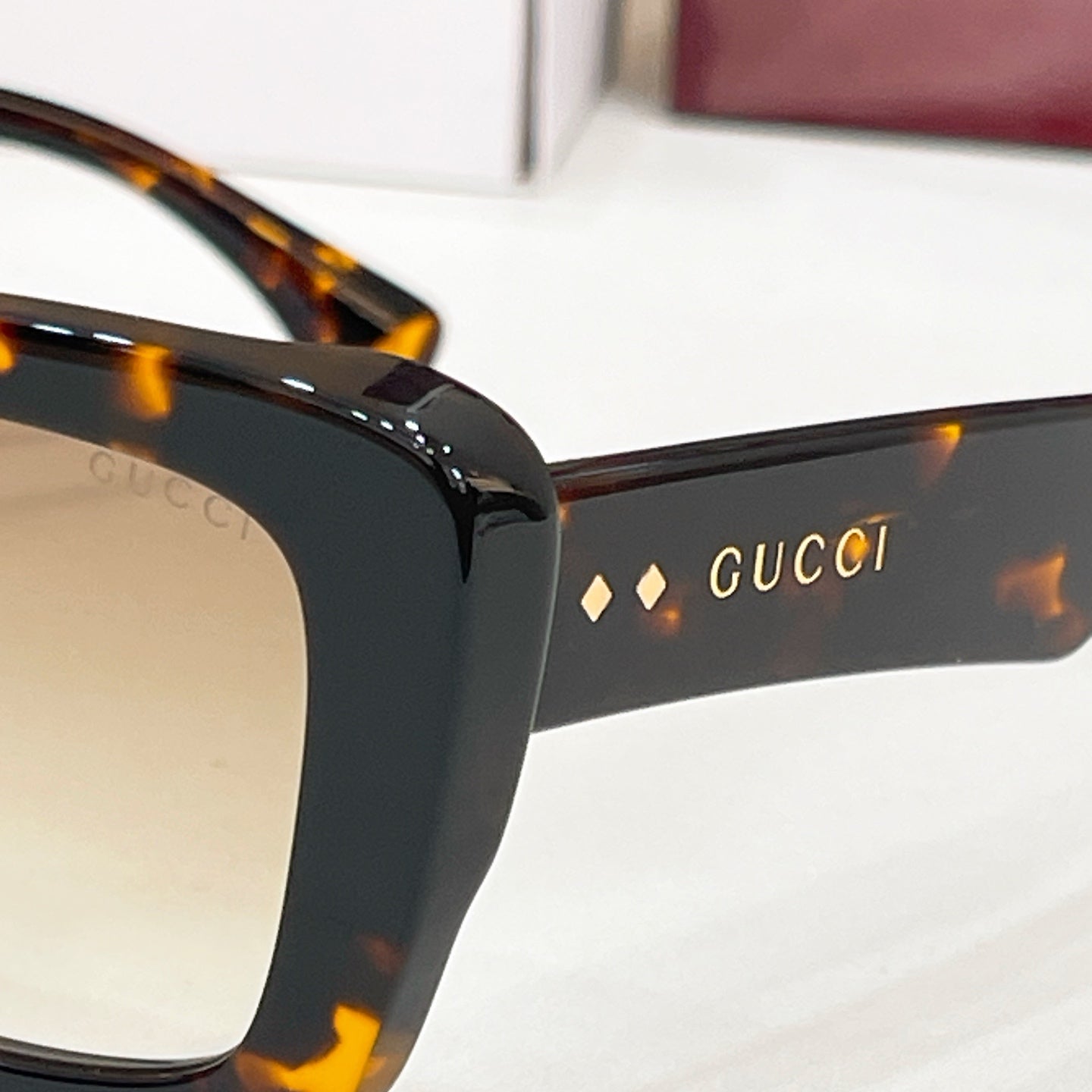 Close-up dark sunglasses arm with Gucci lettering and stud details