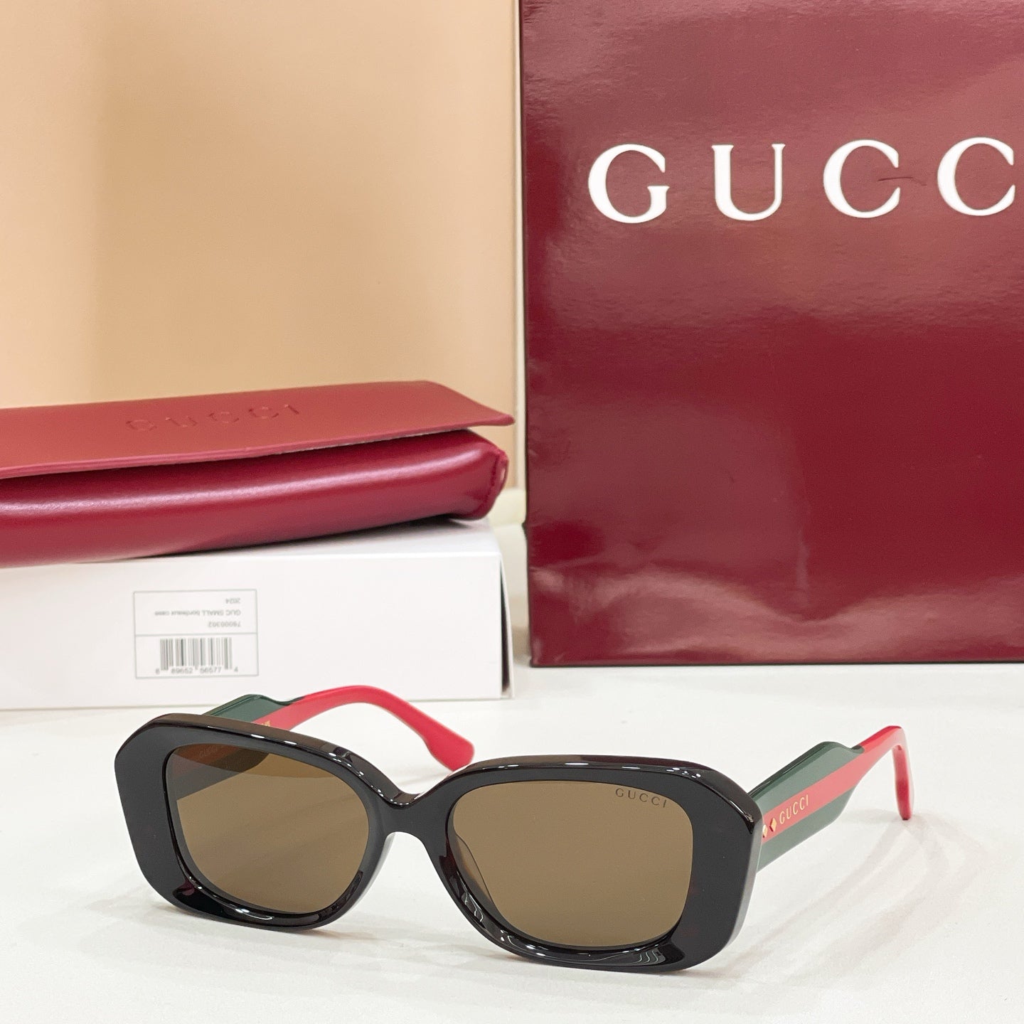 Gucci sunglasses, black cat-eye frames with brown-tinted lenses and red accents