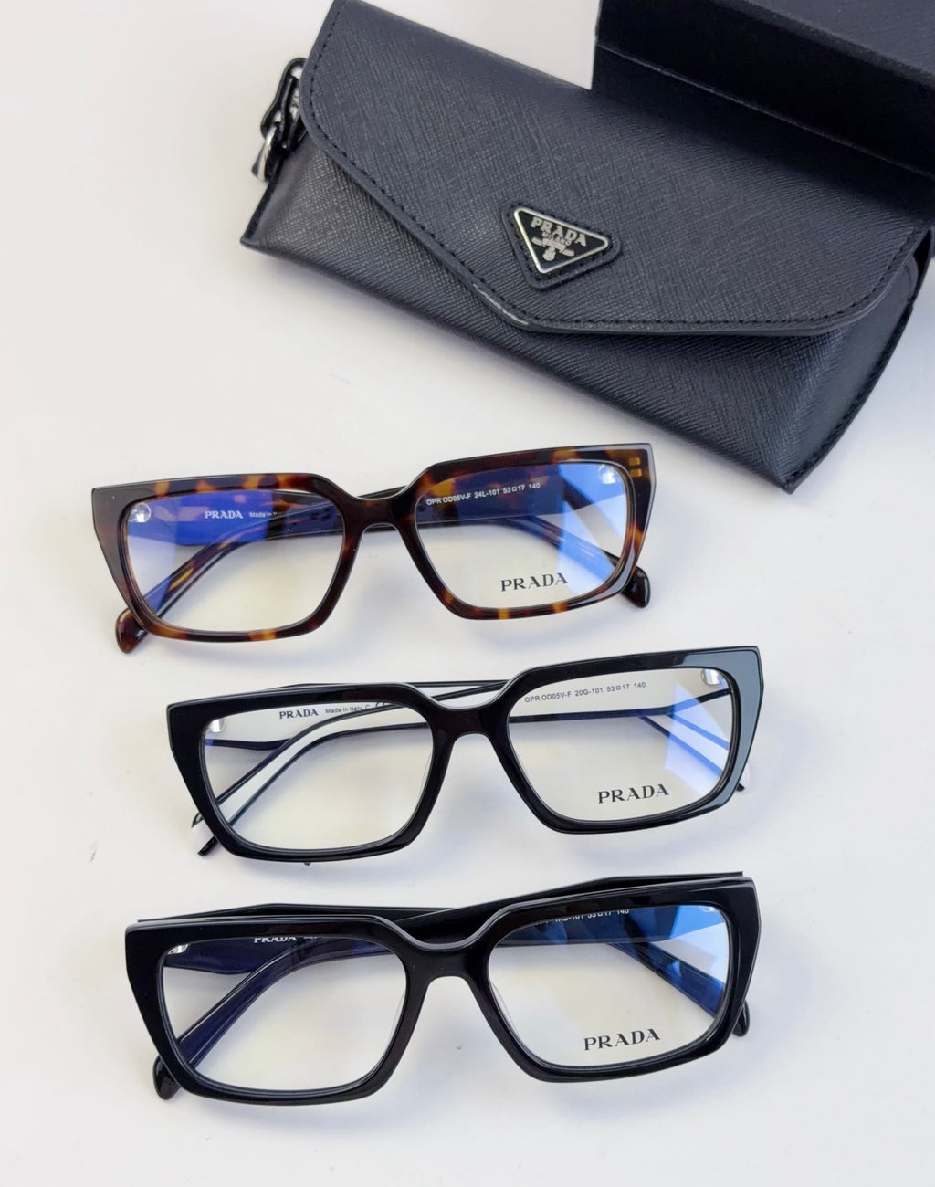 Three eyeglass frames with blue-tinted lenses and matching black case