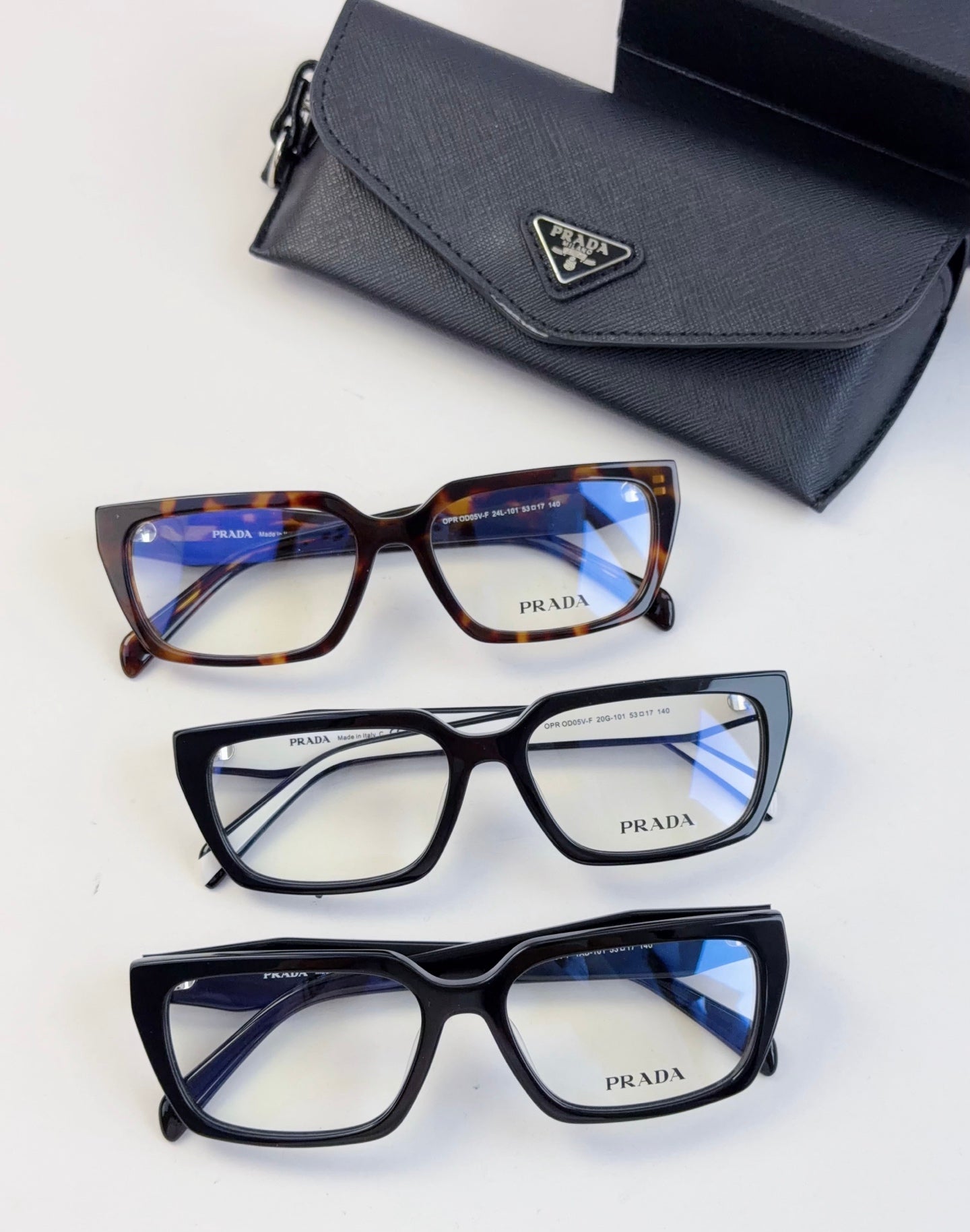 Three eyeglass frames with blue-tinted lenses and matching black case