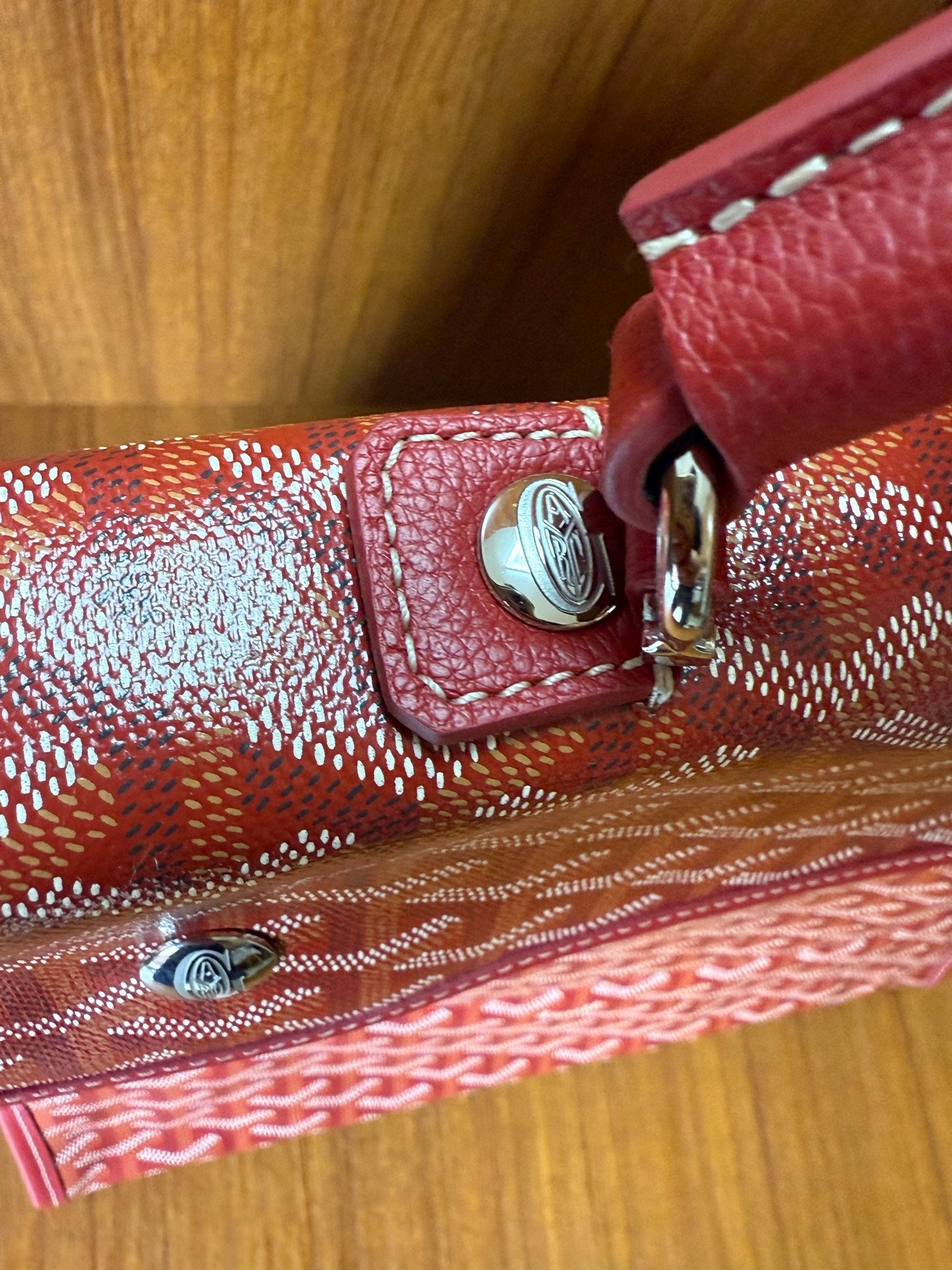 Red Goyard patterned handbag close-up of strap attachment and buckle hardware