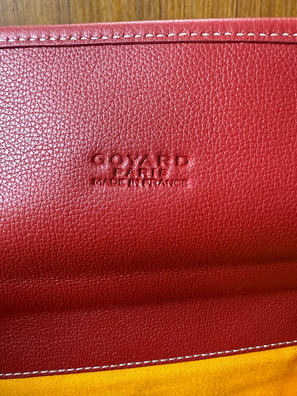 Red Goyard bag leather stamp on textured surface with stitched edge