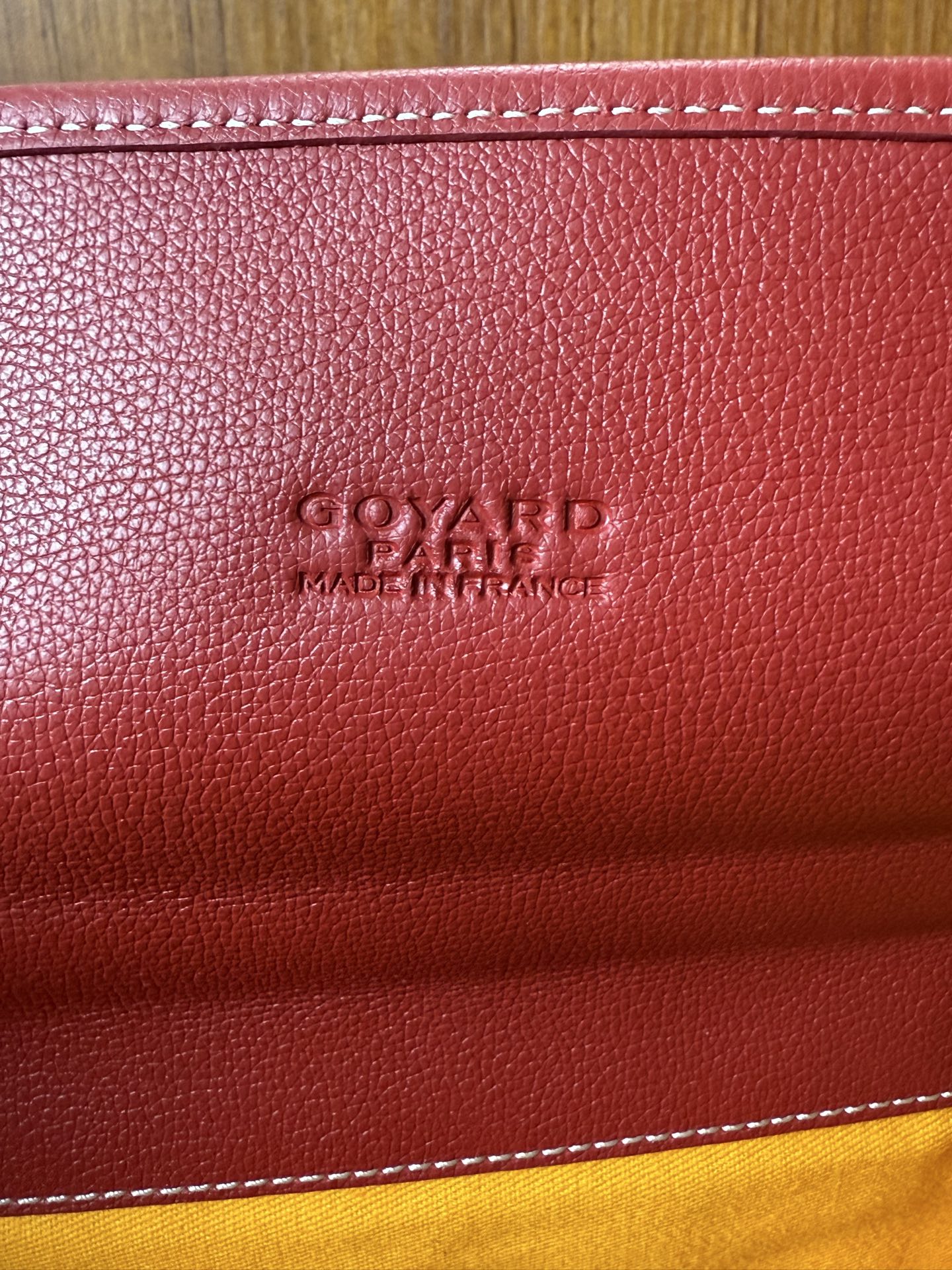 Red Goyard bag leather stamp on textured surface with stitched edge